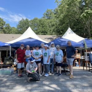 A group of people standing under blue tents.