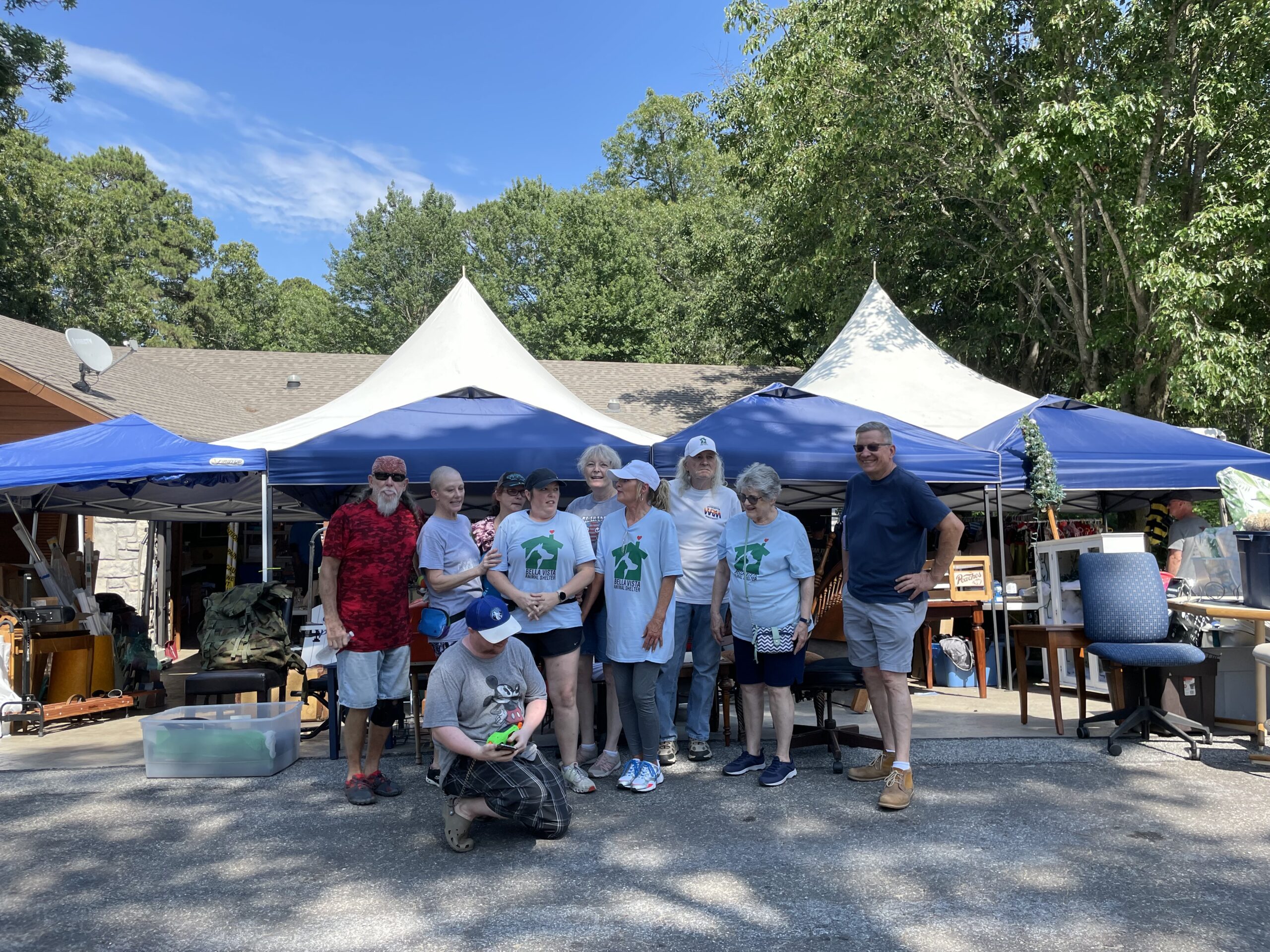 A group of people standing under blue tents.