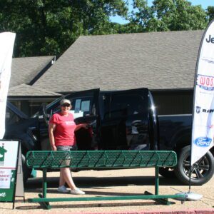 A woman standing on the side of a bench near some flags.