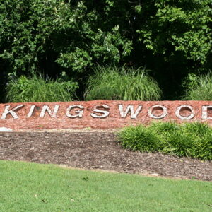 A sign that says kingswood in front of some bushes