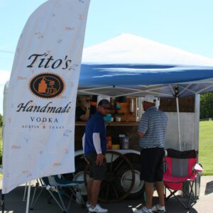 A man standing next to a tent with other people.