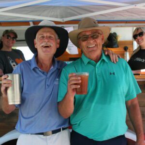 Two men standing next to each other holding drinks.